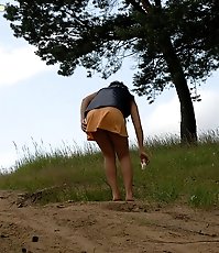 Naughty brunette pisses into a sandpit in forest