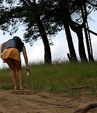 Naughty brunette pisses into a sandpit in forest