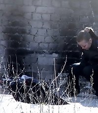 Two girls relieve themselves behind a building